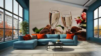 Bride and groom toast and clink glasses with champagne, celebrate wedding in restaurant. Engaged young couple celebrate this special occasion. Wall mural