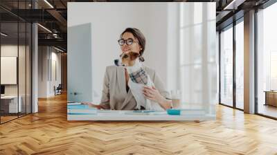 Busy female teacher wears formal clothes and spectacles conducts online lessons for students works at computer poses in coworking space with dog, busy working online. Businesswoman at desktop Wall mural