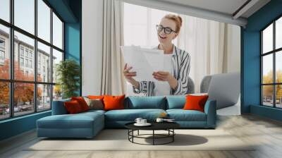 Cheerful professional accountant prepares annual financial report looks at documents Wall mural