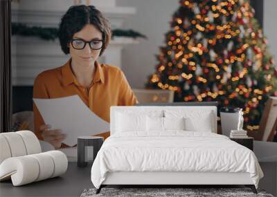 Female entrepreneur working online on laptop at Christmas in office with xmas tree in background Wall mural