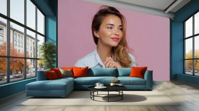 Headshot of beautiful young woman has minimal makeup, looks refreshed, turns aside, has satisfied thoughtful expression, wears blue shirt, thinks about weekend, isolated against purple background. Wall mural