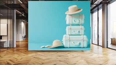 Mint green suitcases stacked artfully with straw hats, against a clean teal background, embodying stylish travel and relaxation themes. Wall mural