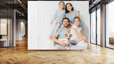 Portrait of happy family indoor. Handsome father holds dog, beautiful brunette mother and two daughters, have fun together, pose for family album, spend time together. People, relationships concept Wall mural