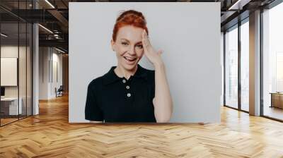 Pretty red-haired woman with hair in bun forgetting something, isolated on grey background Wall mural