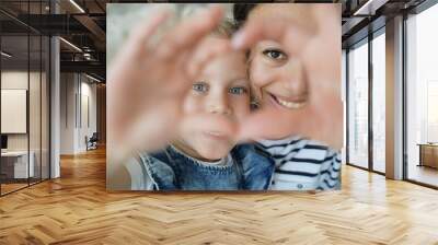 Smiling foster mom, adopted child girl daughter taking selfie, showing love heart gesture together Wall mural