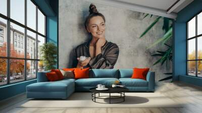 Young beautiful woman with glowing healthy skin broadly smiling while holding face cream Wall mural