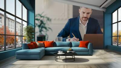 Young handsome executive manager working in front of laptop at home office Wall mural