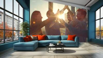 group of professionals in a vibrant office setting, enthusiastically engaging in a team high-five, signifies a moment of celebration or achievement. Wall mural