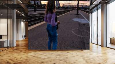 Young girl walking alone on train platform and taking photos on railway station Wall mural