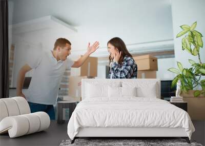 Scandal during the move to a new home. Young couple quarreling in a new apartment near cardboard boxes and. Wall mural