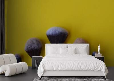 Professional cosmetic makeup brushes of different sizes on a yellow background for applying powder, shadows and blush and other cosmetic products Wall mural