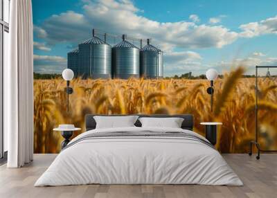 Lush wheat field under a vibrant blue sky, featuring three metallic silos. Captures the essence of rural agriculture and grain storage in a tranquil landscape. Wall mural