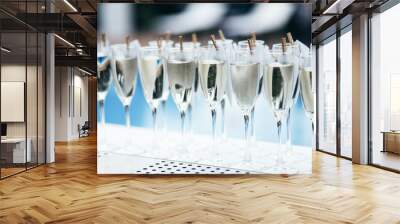 Glasses with cold sparkling wine standing on a counter in a row, swimming pool in back, party bar Wall mural