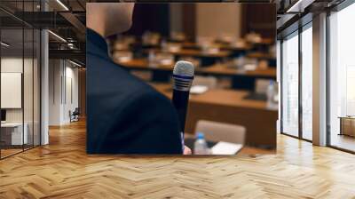 Microphone in hand of man in suit on background of empty conference hall. Rehearsal of public speaking Wall mural