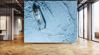 Perfume bottle on blue water wavy background. Fresh sea fragrance concept. Women's and men's essence. Wall mural