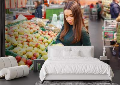 Woman holding two apples in a market. Wall mural