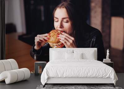 Close up portrait of woman biting burger. Happy hungry girl in a restaurant Wall mural