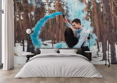 Couple  hugging  in winter forest with colored smoke Wall mural