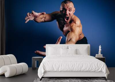 Super emotional bodybuilder screaming and showing muscles on blue background. Fit man with muscular body Wall mural