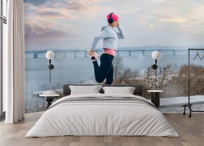 Young athlete stretching on a winter day near city background Wall mural