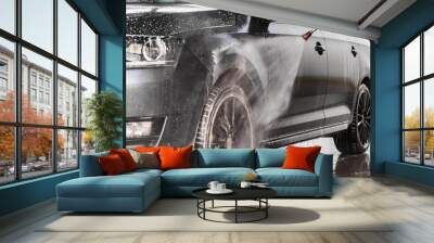 A man is washing a car at self service car wash. High pressure vehicle washer machine sprays foam. Wall mural