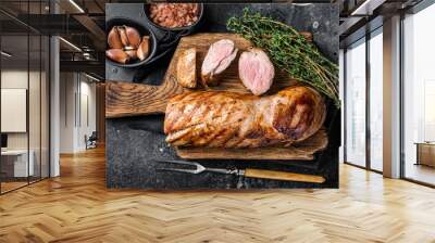 BBQ roasted pork tenderloin fillet meat on wooden board with herbs. Black background. Top view Wall mural