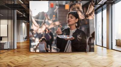 Beautiful young female tourist in city of Paris France enjoying holidays in beautiful little street festival eating street food Wall mural