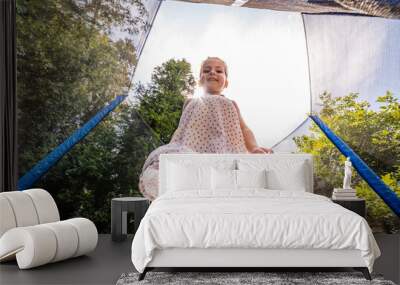 Little happy toddler girl jumping on her trampoline outside on a summer day. Kid jumping on trampoline.  Wall mural