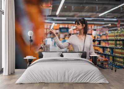 sale, shopping, consumerism and people concept. woman in supermarket with shopping trolley choosing  Wall mural