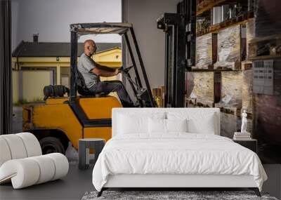 Warehouse man worker with forklift. Warehouse worker driver in loading by forklift stack loader Wall mural