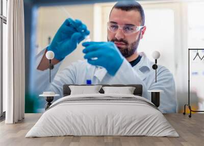 Young handsome scientist in laboratory working with test tubes and doing research Wall mural