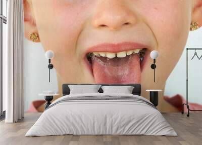 Cheerful child. Girl laughs close-up of the face on a white background. A little girl show tongue throat. portrait with wide open mouth and protruding tongue. with clear view pulls out long tongue Wall mural