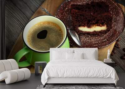 Chocolate cake and a green cup of coffee close-up on a wooden table. View from above. Coffee. Wall mural