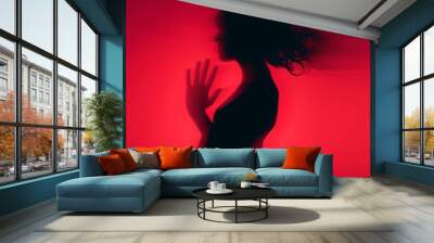 Female blurred silhouette on a red background. Elegant outline of a woman in motion out of focus Wall mural