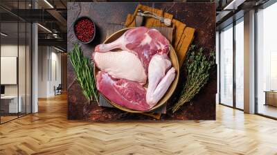 Fresh duck meat parts, raw breast steak, legs, wings in a plate with herbs. Dark background. Top view Wall mural