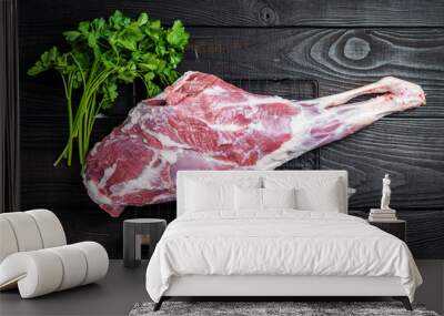 Fresh Raw whole lamb mutton leg thigh on kitchen table with herbs. Black Wooden background. Top view Wall mural