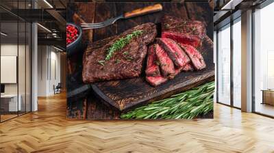 Grilled sliced skirt beef meat steak on a cutting board with herbs. Dark wooden background. Top view Wall mural