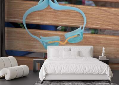 Blue swimming glasses lie on a brown wooden sunbed on a Sunny summer day on the beach while on vacation. Wall mural