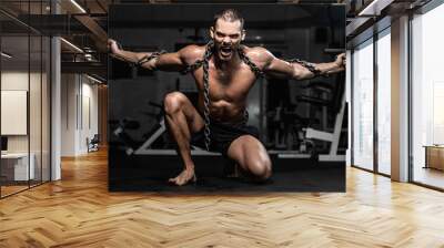 Muscular man slave in chains in gym, the prisoner Wall mural