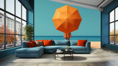 Person holding large orange umbrella on beach. Wall mural