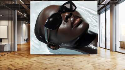 Portrait of a model laying in water wearing dark sleek sunglasses. Beautiful black woman in fashion editorial style  Wall mural