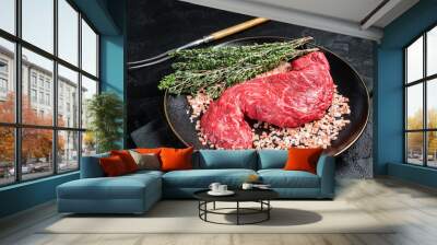 Raw Machete beef meat steak or hanging tender cut on plate with sea salt and thyme. Black background. Top view Wall mural