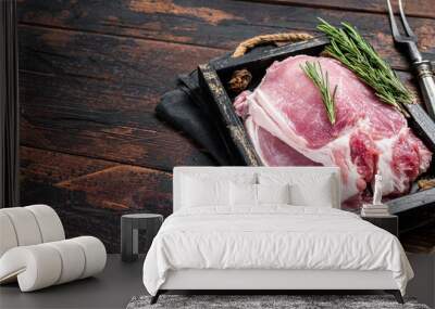 Ready for cooking raw pork chop steaks in a wooden tray with rosemary. Wooden background. Top view. Copy space Wall mural