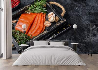 Smoked sliced salmon fillet in a wooden tray with herbs. Black background. Top view. Copy space Wall mural