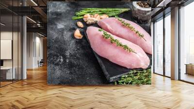 Turkey raw breast fillet steaks on marble board with herbs. Black background. Top view. Copy space Wall mural