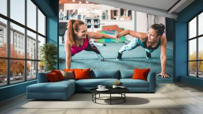 Two female friends exercising together in the gym Wall mural