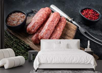 Uncooked Raw beef and lamb meat kebabs sausages on a wooden board. Black background. Top view Wall mural