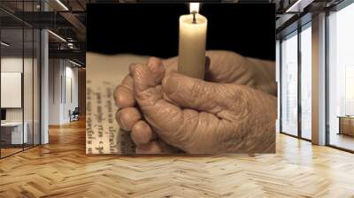 Old female hands with a candle Wall mural