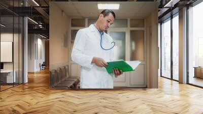 Young doctor looking at a folder in the hospital Wall mural