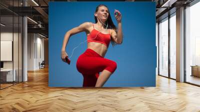 Young fitness woman running on sky backround. The concept of a healthy lifestyle Wall mural